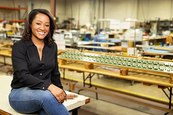 President and CEO of Electro Soft, Inc Karla Trotman sitting in a workshop, smiling towards the camera